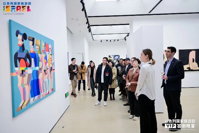 A group of people standing in a line in a room with a painting Description automatically generated