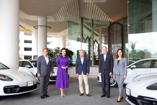 A group of people standing in front of a car Description automatically generated