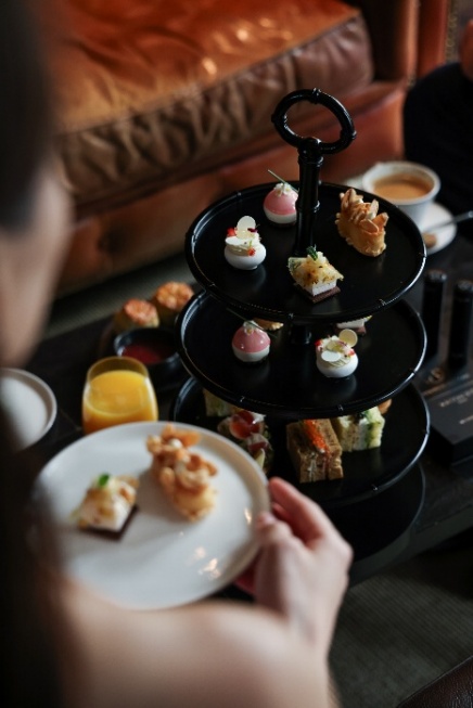 A person holding a plate of desserts

Description automatically generated